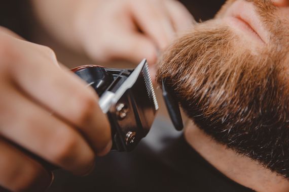 Friseure schneiden Haare in einem rustikalen Friseursalon mit Backsteinwänden und Spiegeln.