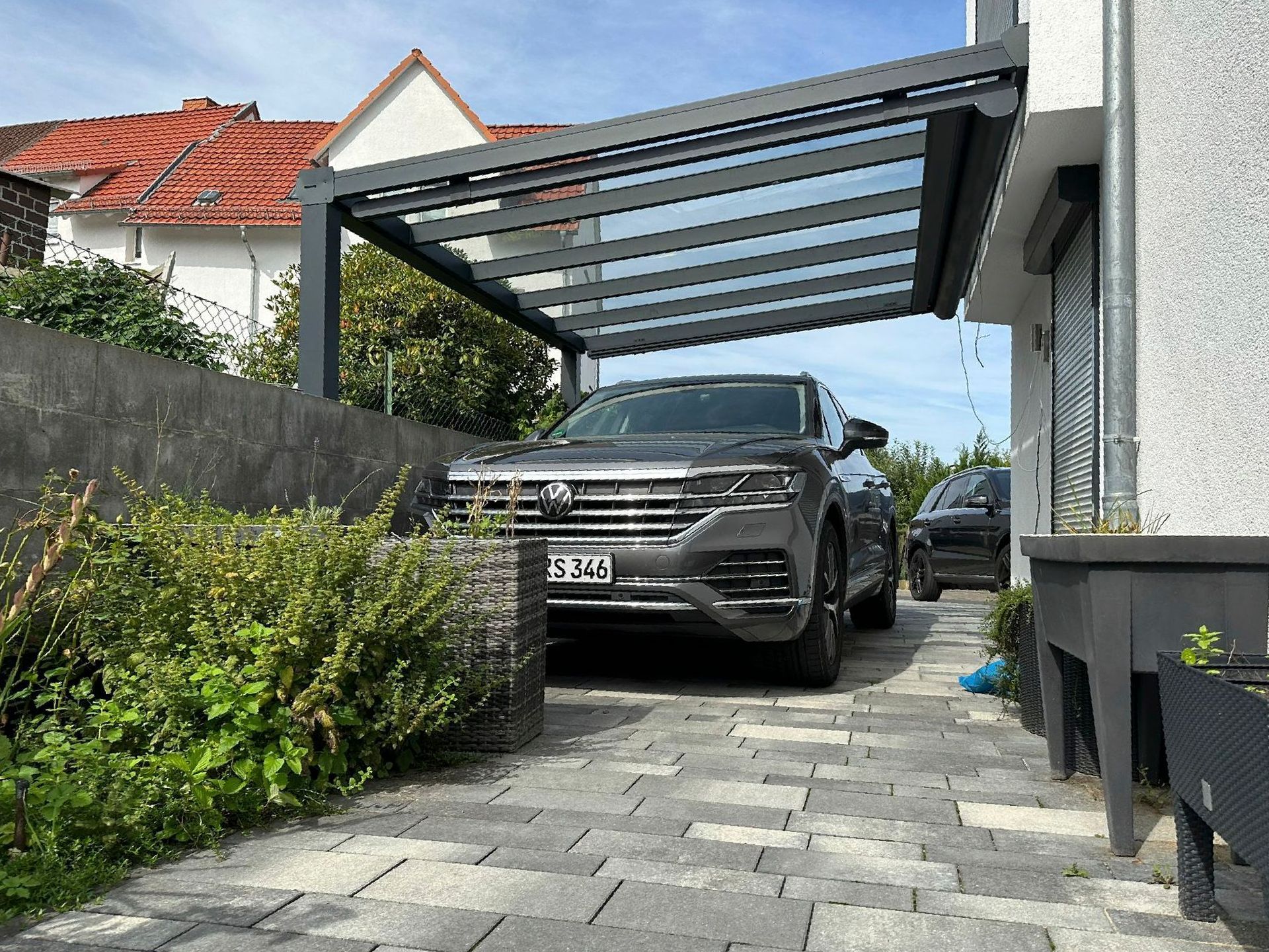 Ein Auto ist unter einem Vordach vor einem Haus geparkt.