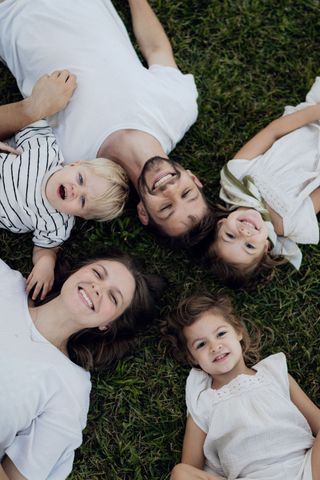 Quatre personnes allongées en cercle sur l'herbe, souriant à l'objectif.