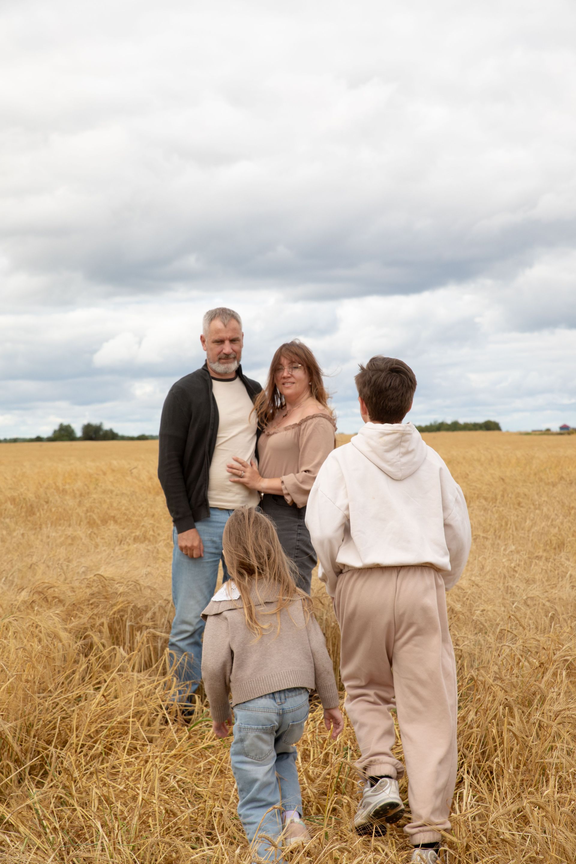 Une famille réunie dans un champ de blé sous un ciel nuageux