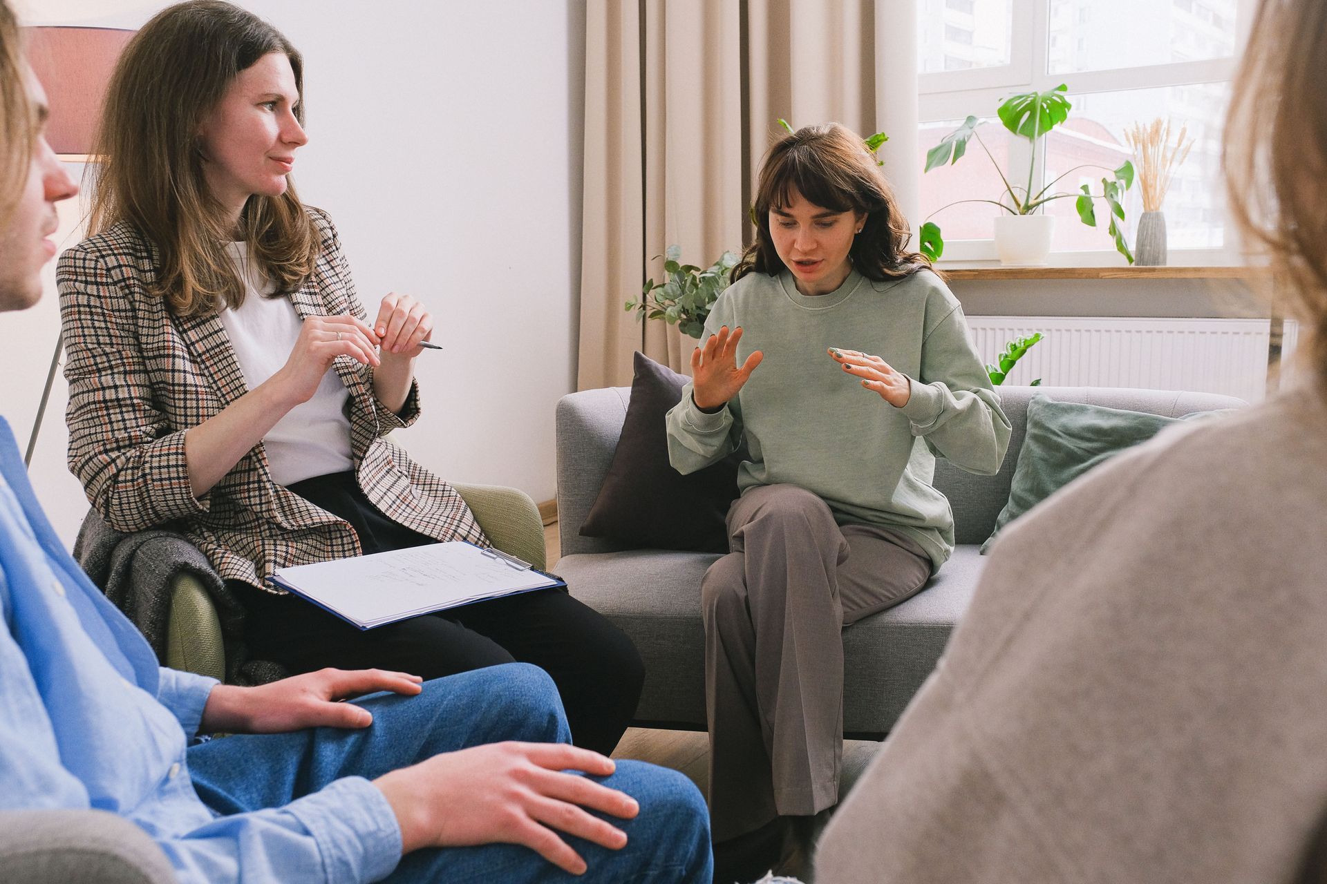 Des personnes assises dans un salon, participant à une discussion de groupe sur un canapé.