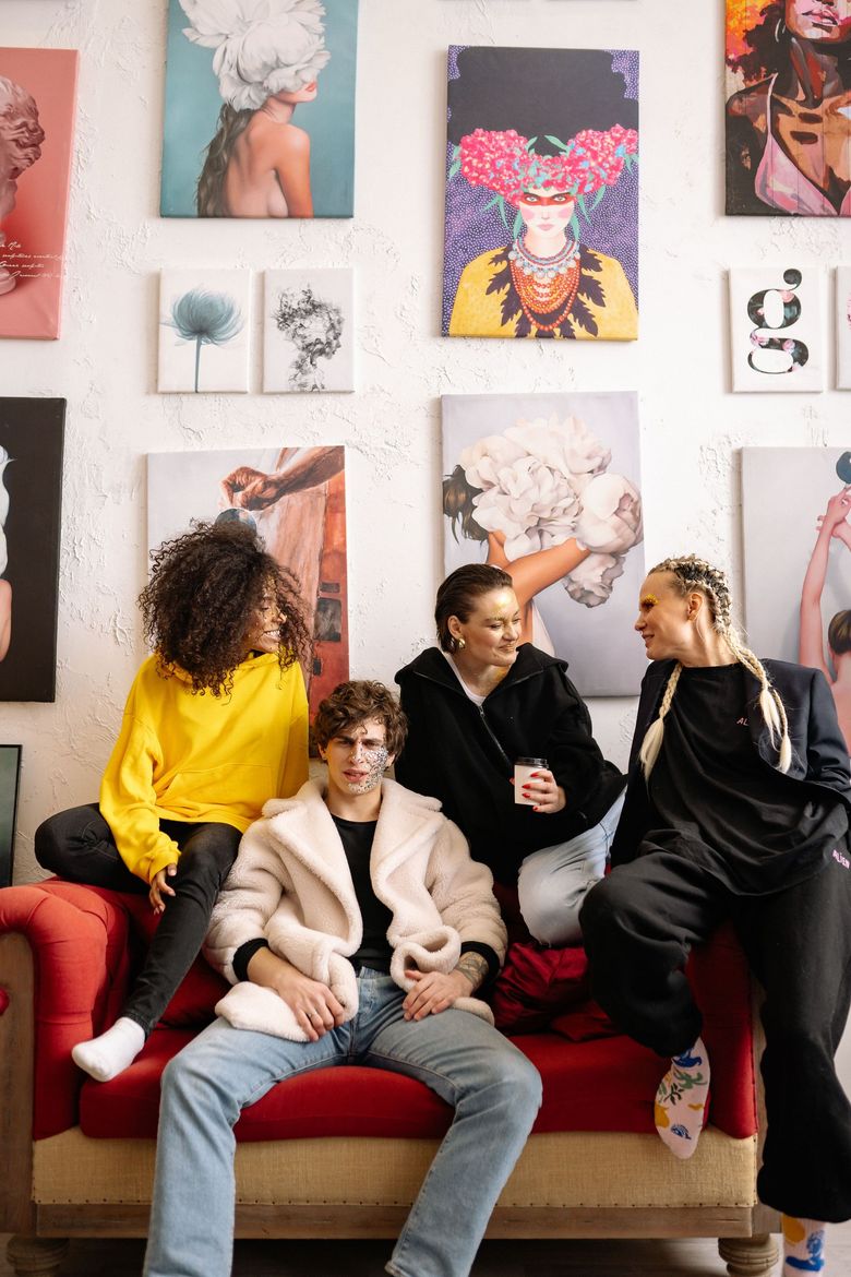 Quatre amis se détendent sur un canapé rouge dans une vitrine colorée d'une galerie d'art.