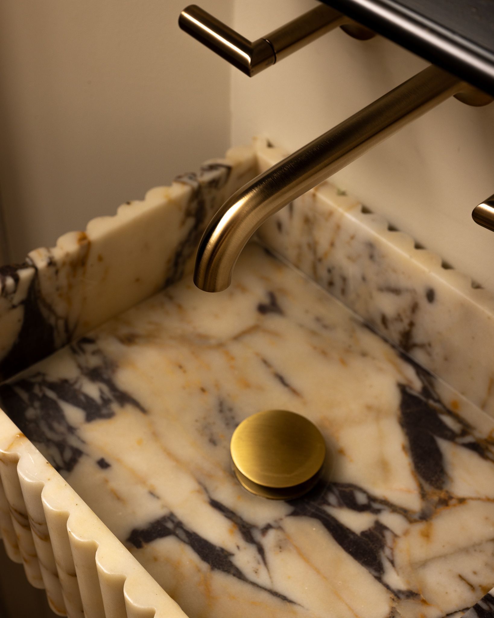 Marble tray with a brass knob and metal handles against a beige background