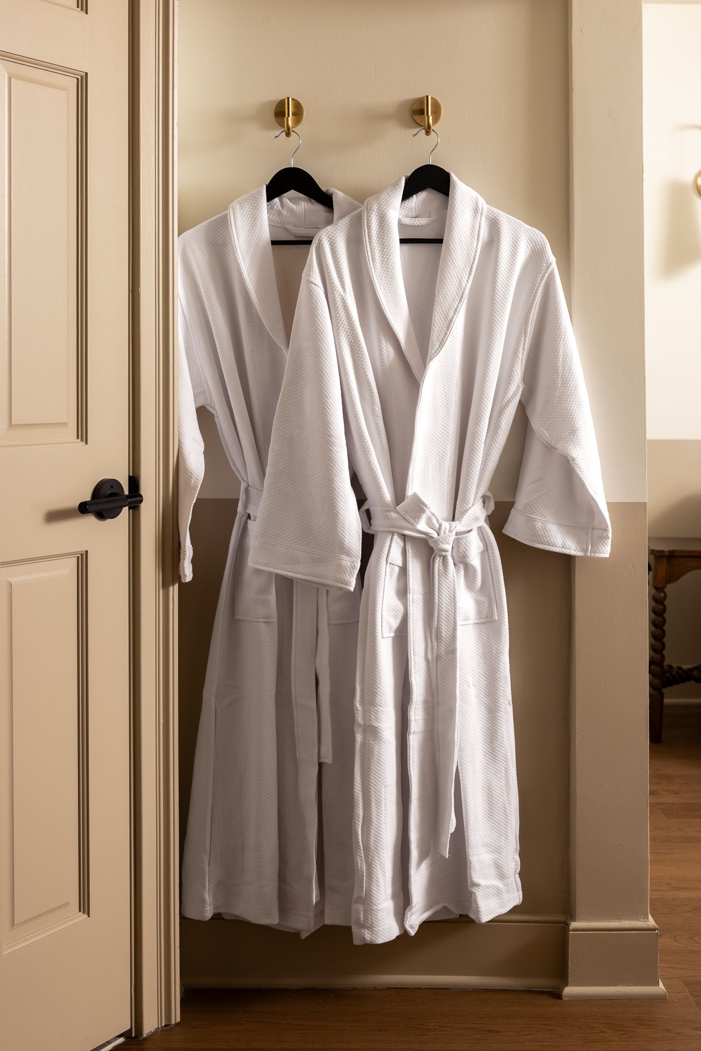 White bathrobe hanging on a closet door in a bedroom.
