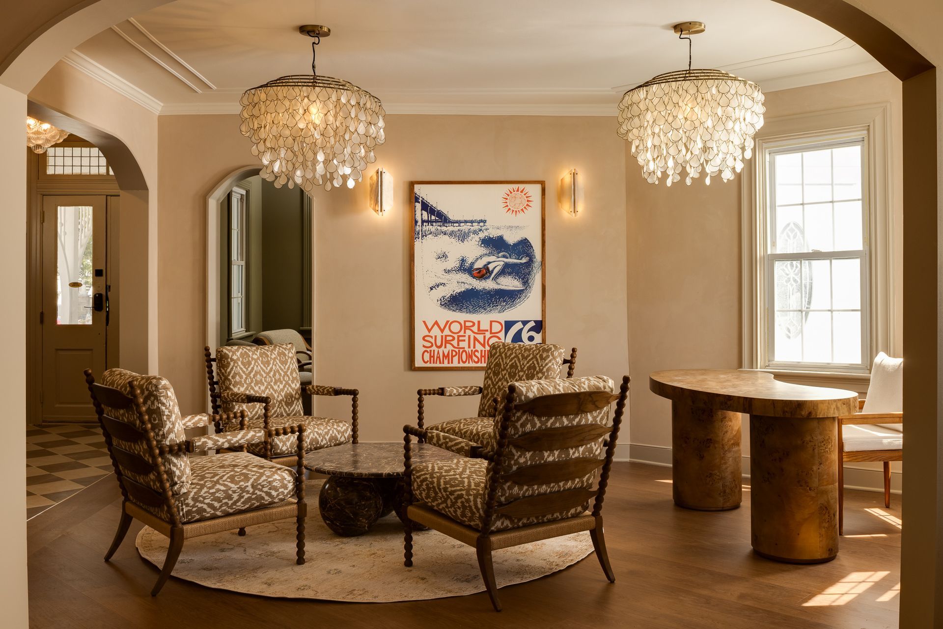 Elegant living room with tufted sofas, floral decor, ornate mirror, canopy bed, and sunlit windows