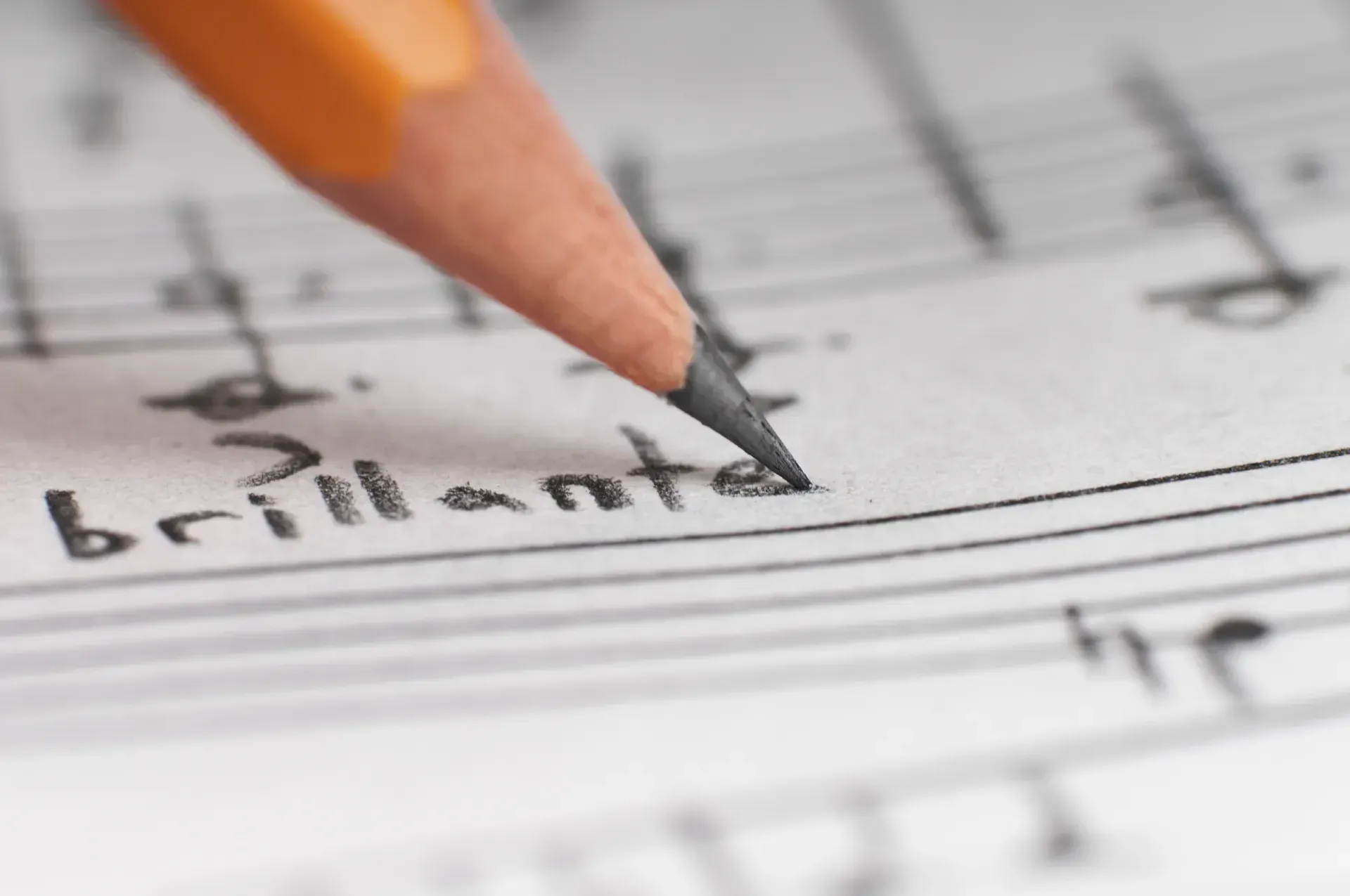 Una persona está escribiendo la palabra brillante en una partitura.