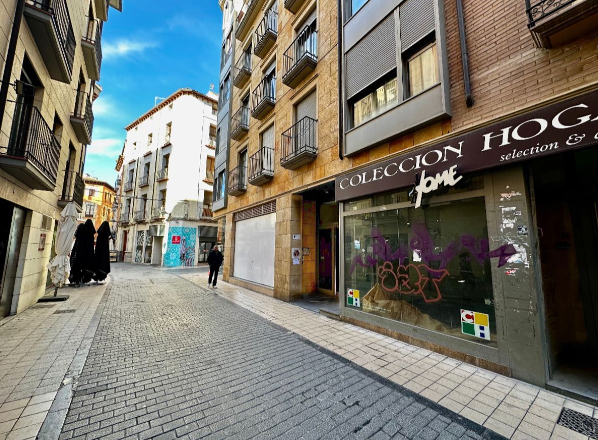 Un hombre camina por una calle adoquinada frente a un edificio.