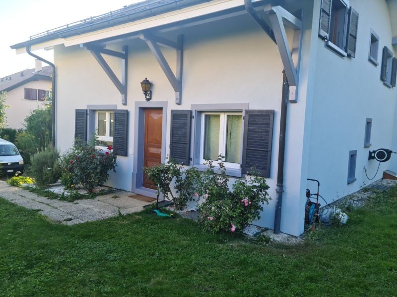 Une maison blanche avec une voiture garée devant.