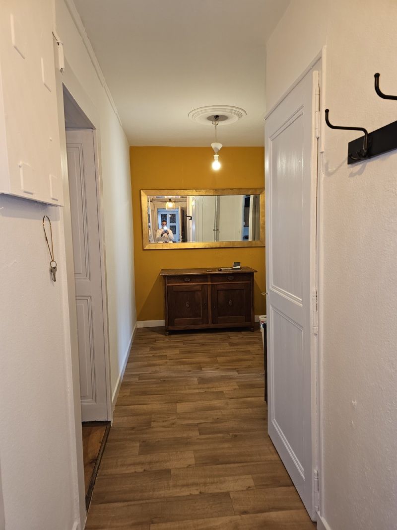 Un long couloir avec du parquet et un miroir au mur.