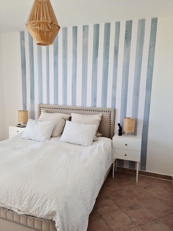 Une chambre avec un lit, des tables de nuit et un mur rayé.