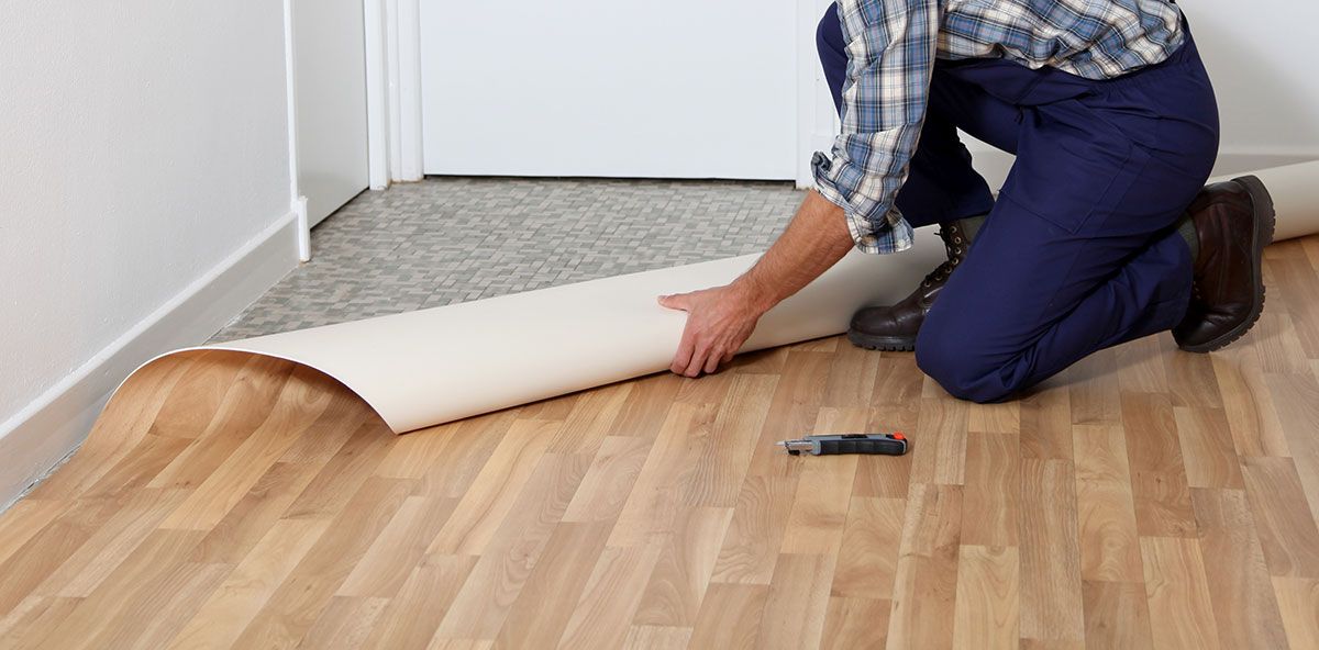 Ouvrier qui pose du lino sur du carrelage