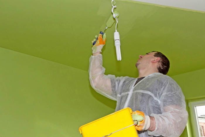 Une personne en train de peindre le plafond en vert