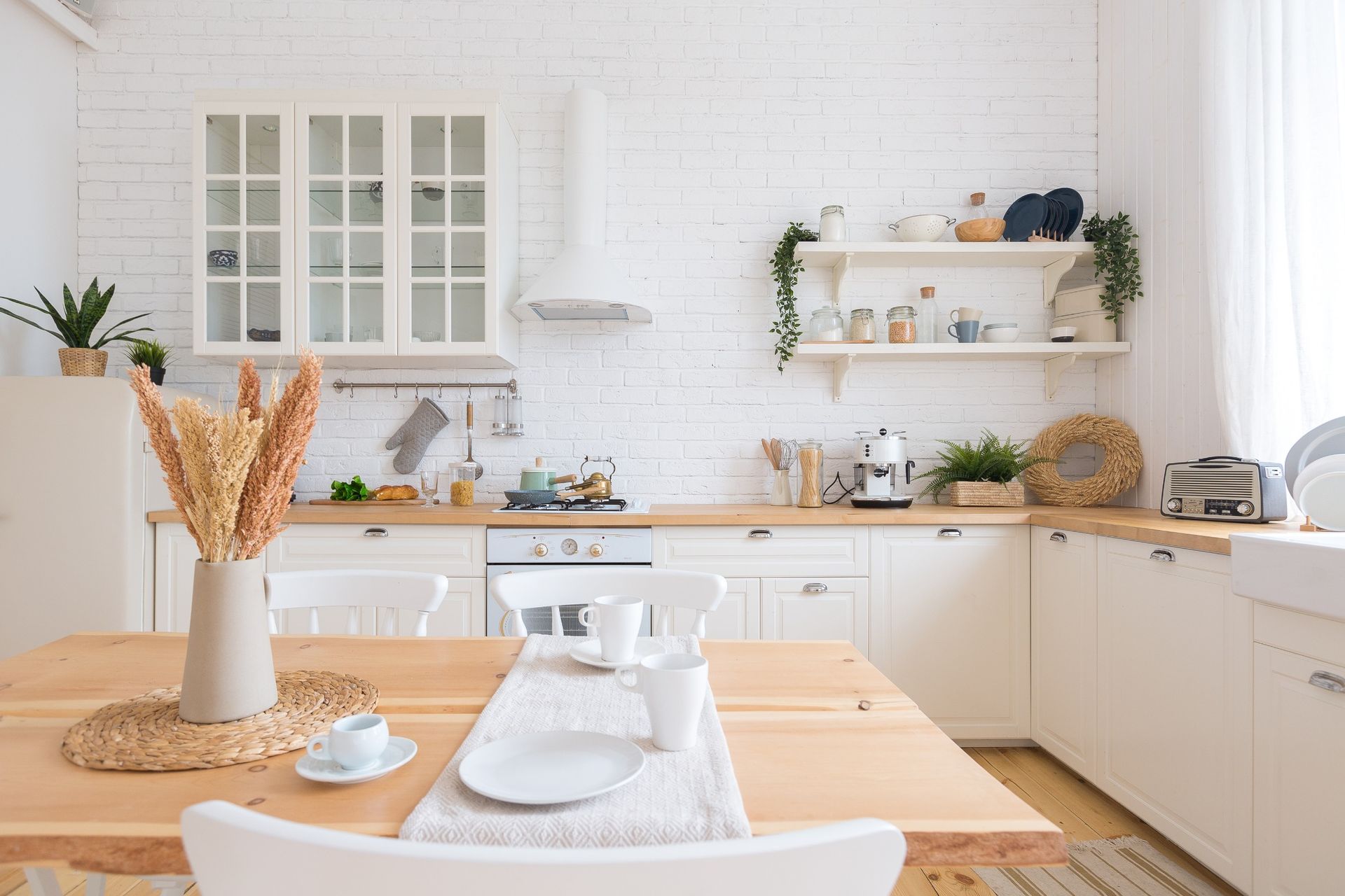 Una cocina con gabinetes blancos y una mesa y sillas de madera.
