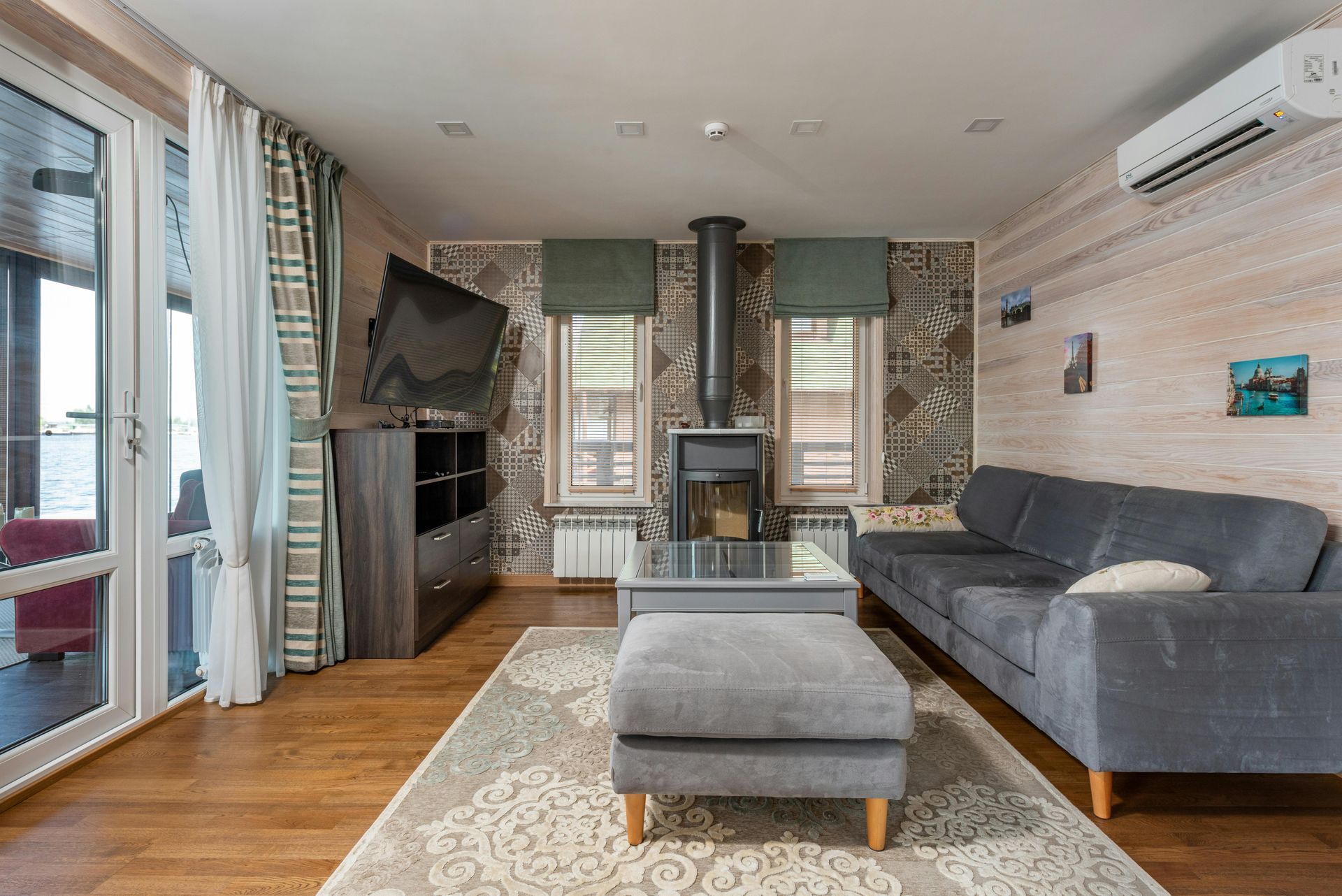 Una sala de estar con sofá, otomana, mesa de café y televisión.