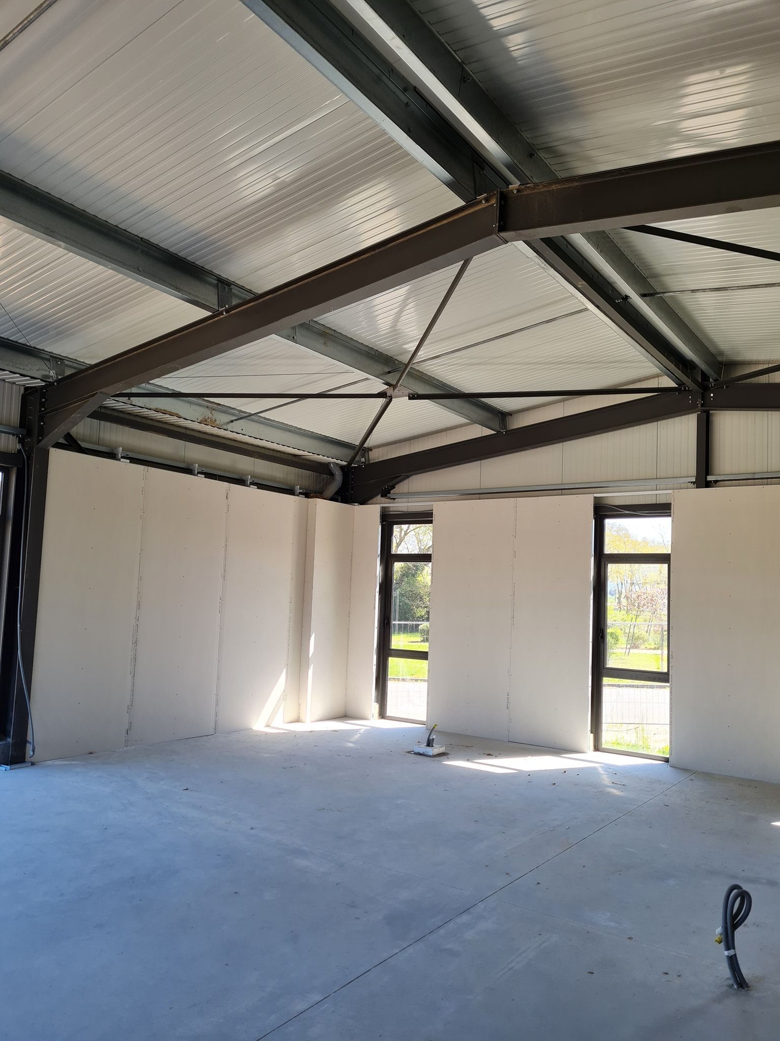 Pose de plaques de plâtre dans un hangar