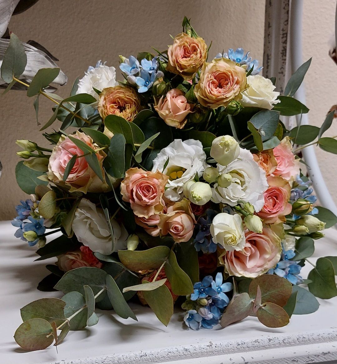 Die Braut hält einen Strauß weißer Rosen und Schleierkraut; Schleier und Brautkleid sind sichtbar.