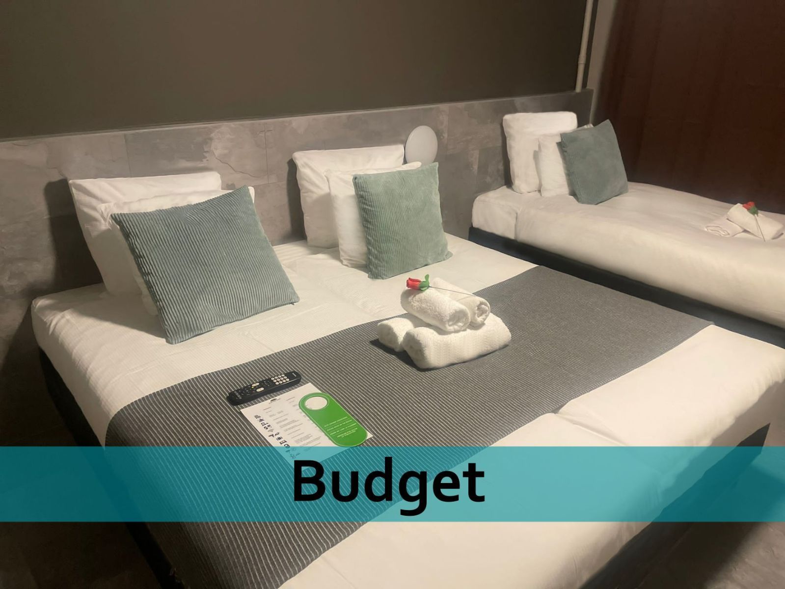 Een hotelkamer met drie bedden en een bordje met de tekst budget.