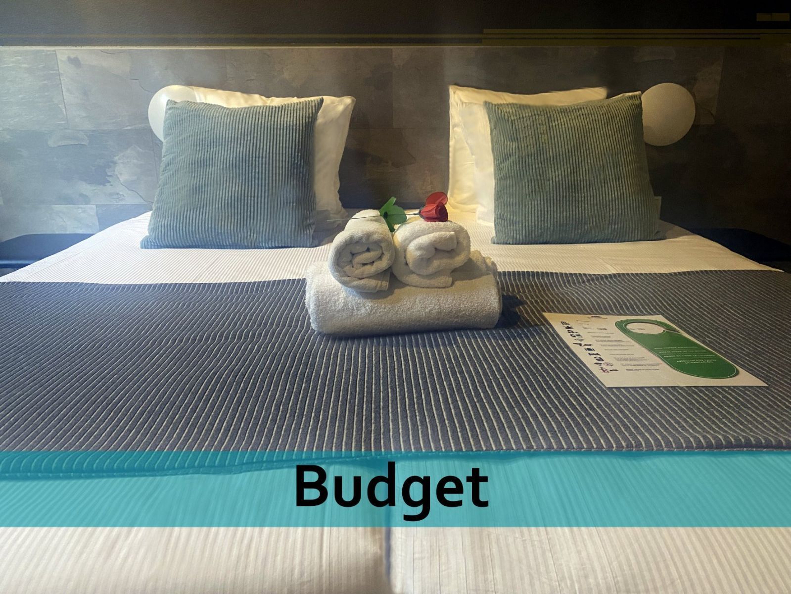 Een bed met kussens en handdoeken erop en het woord budget onderaan