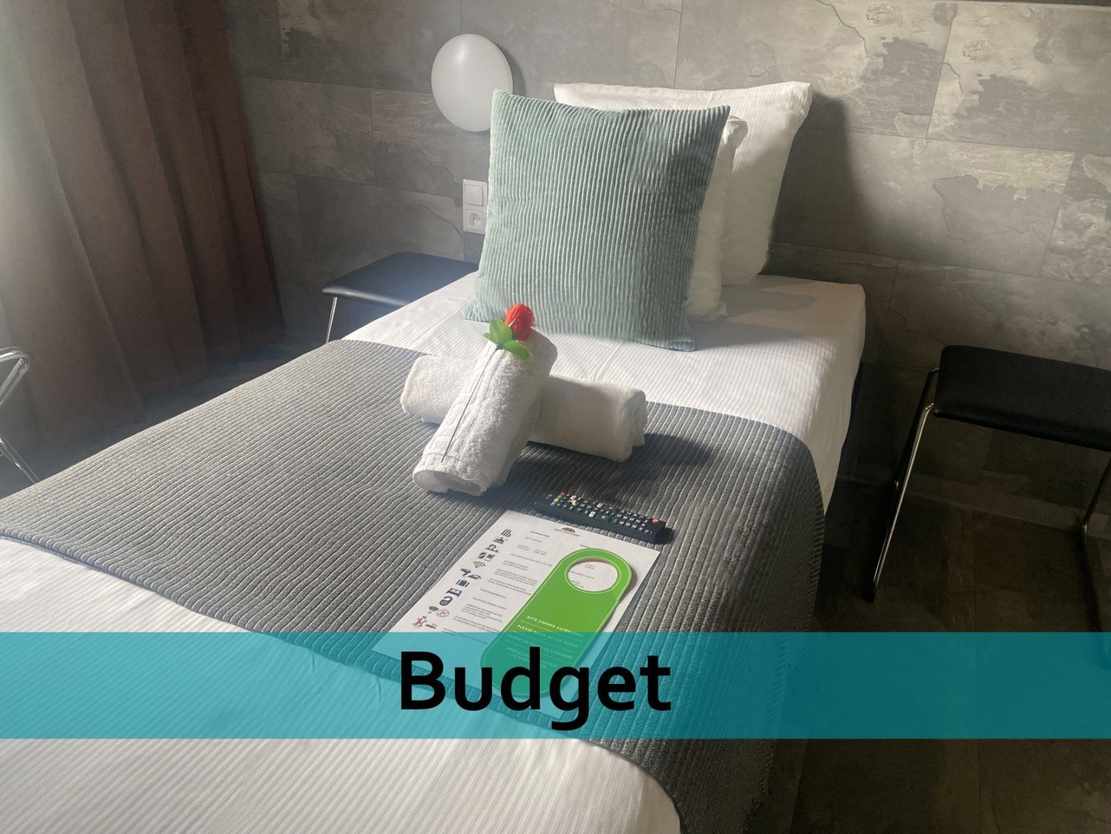 Een hotelkamer met een eenpersoonsbed en een bordje met de tekst budget