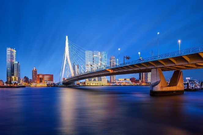 A bridge over a body of water with a city in the background at night.