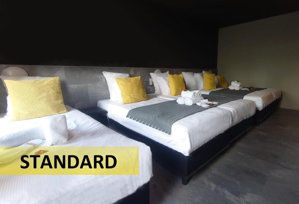 Een hotelkamer met drie bedden en een bordje met de tekst 'standaard'.