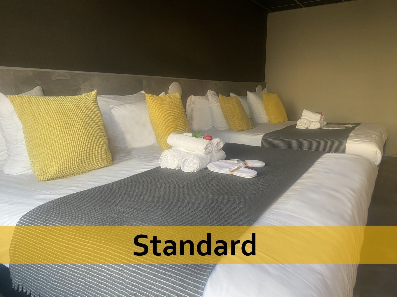 Een hotelkamer met drie bedden en een bordje met de tekst standaard