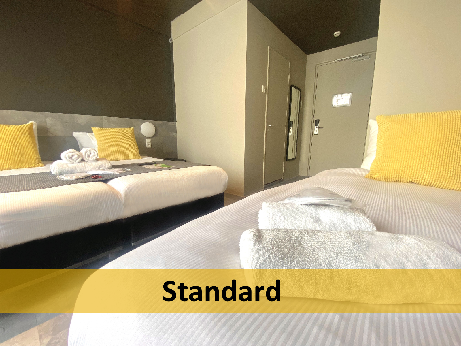 Een hotelkamer met twee bedden en een bordje met de tekst standaard