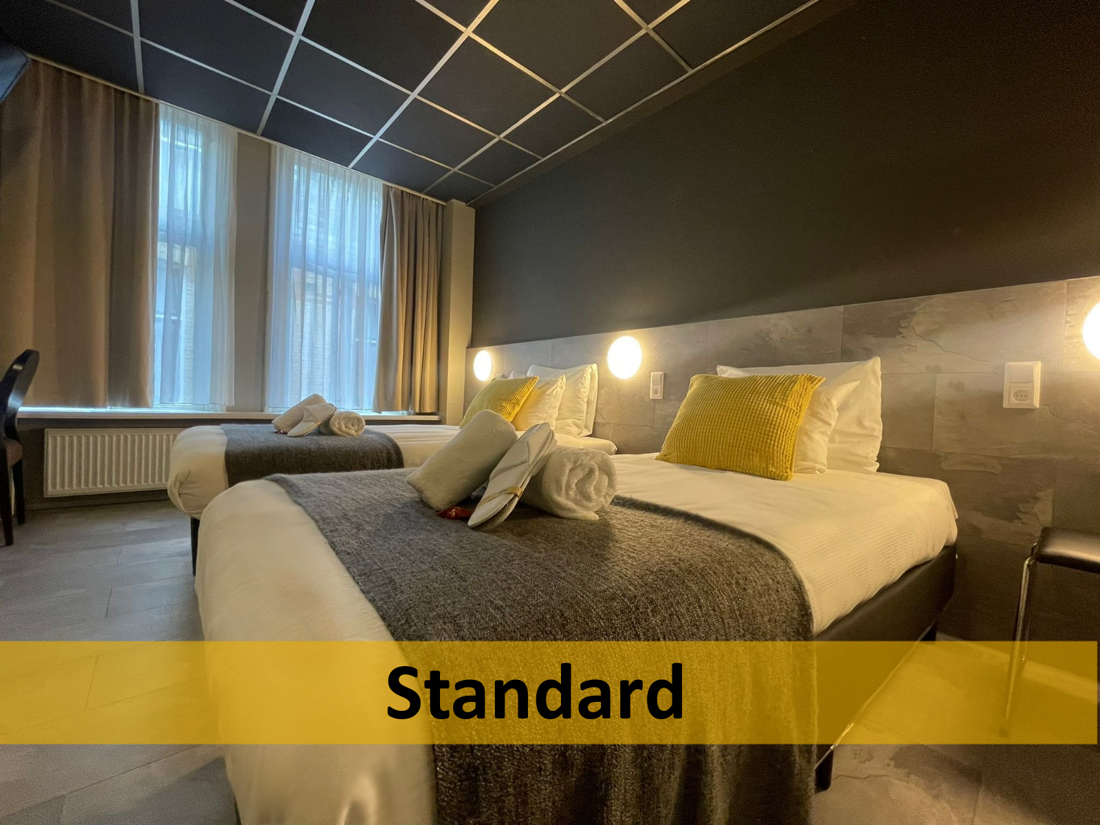 Een hotelkamer met twee bedden en een bordje met de tekst standaard