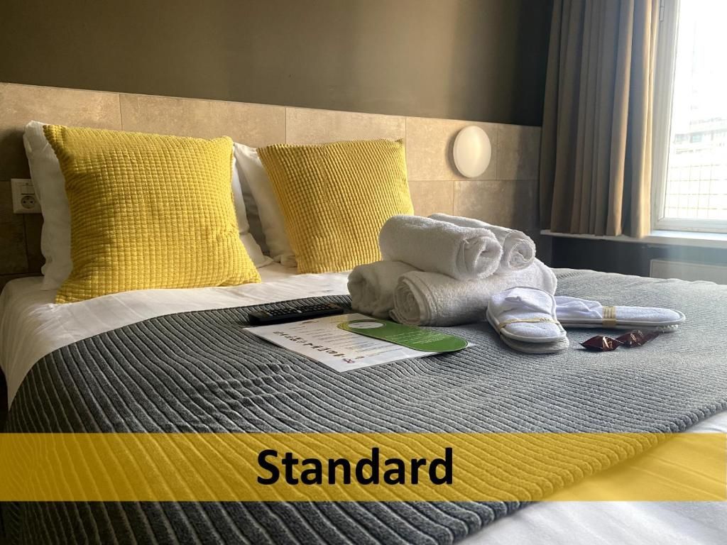 Een hotelkamer met een bed, kussens, handdoeken en een raam.