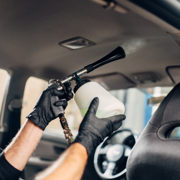 Une personne portant des gants noirs nettoie le ciel de toit d'une voiture .
