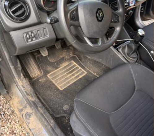 Intérieur sale d'une Renault. La boue et la saleté recouvrent les tapis de sol, les pédales et les surfaces intérieures.