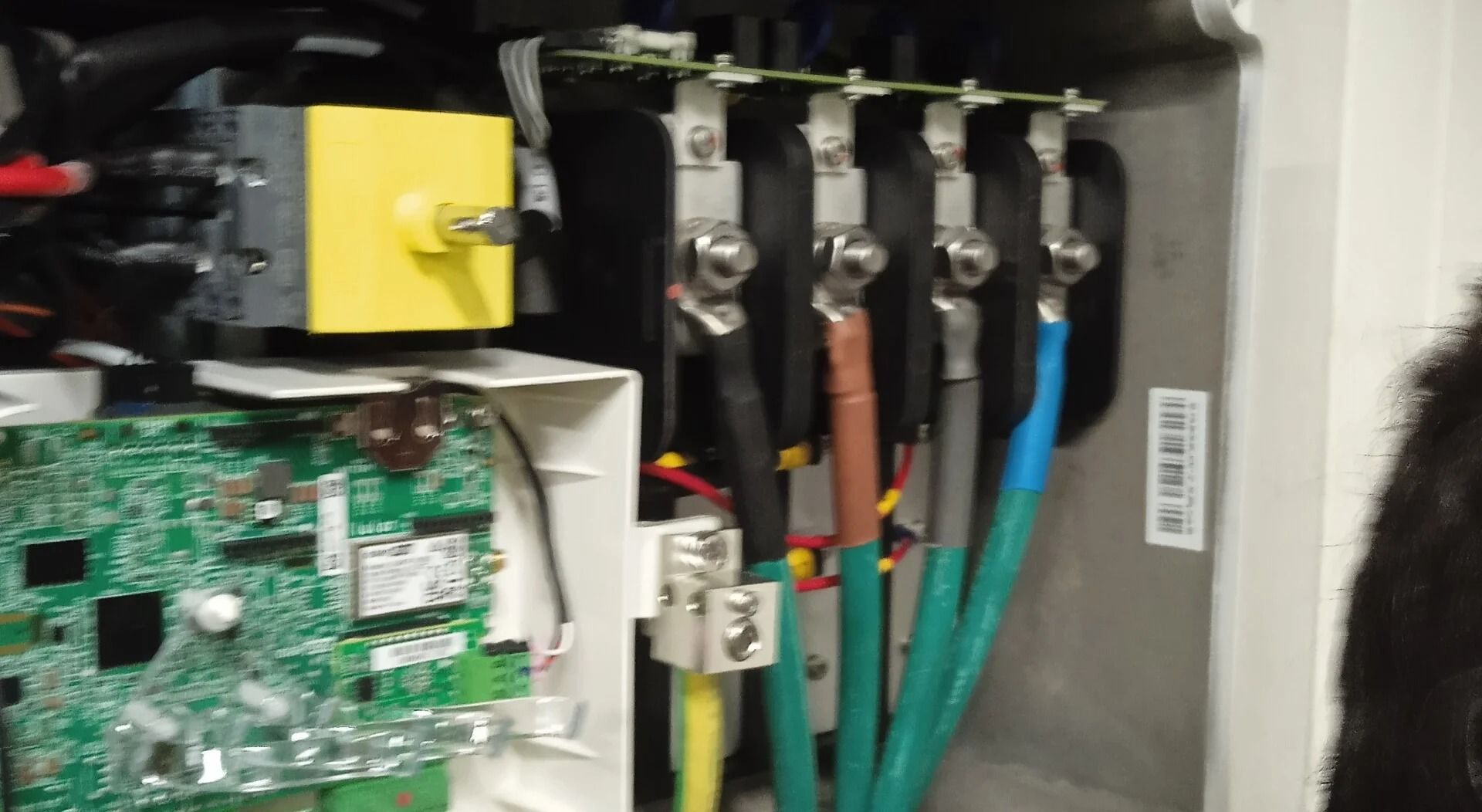 Panel eléctrico con placa de circuito, componente amarillo y cables de colores agrupados conectados a terminales metálicos.