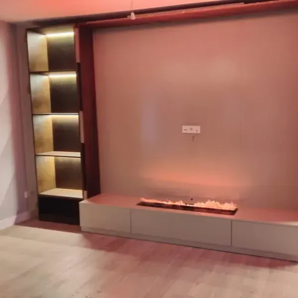 Una pared de sala de estar con una consola de color claro, estanterías iluminadas integradas y una elegante chimenea