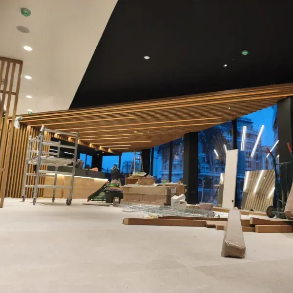 Interior de un edificio en construcción, en el que destaca un prominente techo inclinado de listones de madera.