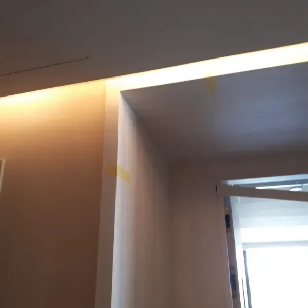 Un rincón de la habitación con una tira de luz empotrada en el techo que crea un brillo cálido.