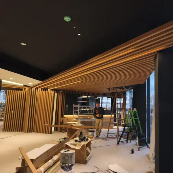 Una persona trabaja en un espacio interior en construcción que cuenta con un techo de listones de madera