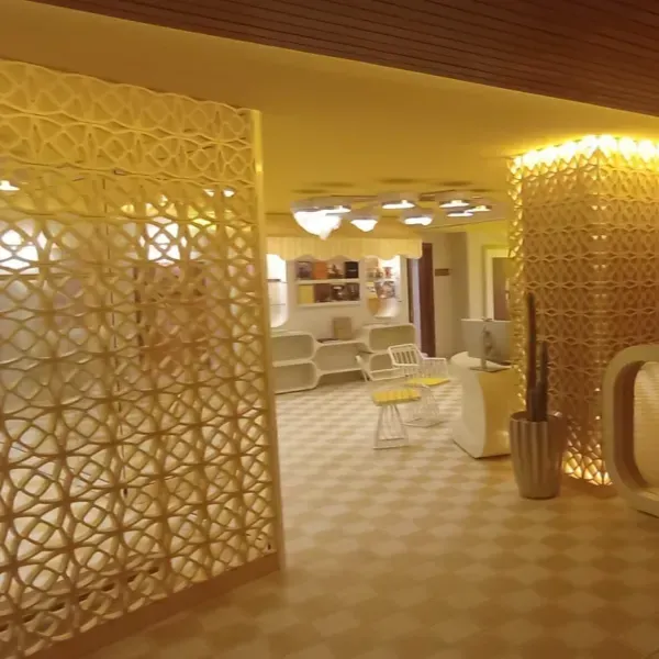 Vista interior de una habitación moderna con celosías decorativas, piso a cuadros, iluminación suave y muebles minimalistas.