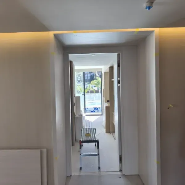 Una vista a través de una puerta minimalista hacia una habitación luminosa y moderna en construcción