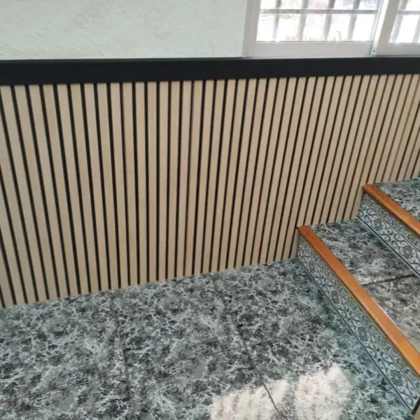 Un panel de pared de listones de madera con un borde negro, ubicado junto a unas escaleras con diseño de mármol.