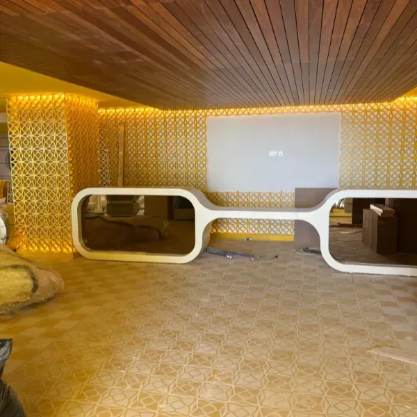 Un escritorio blanco moderno y escultural en una habitación con paredes doradas estampadas, iluminación empotrada.