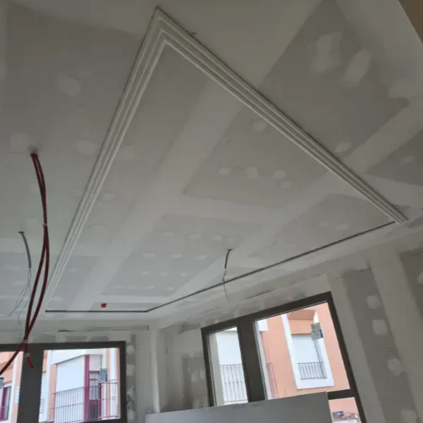 Una toma interior de una habitación en construcción con paneles de yeso blancos en el techo y las paredes.