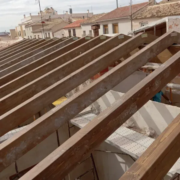 Una vista elevada de cerchas de techo de madera que se instalan sobre un edificio residencial en construcción.