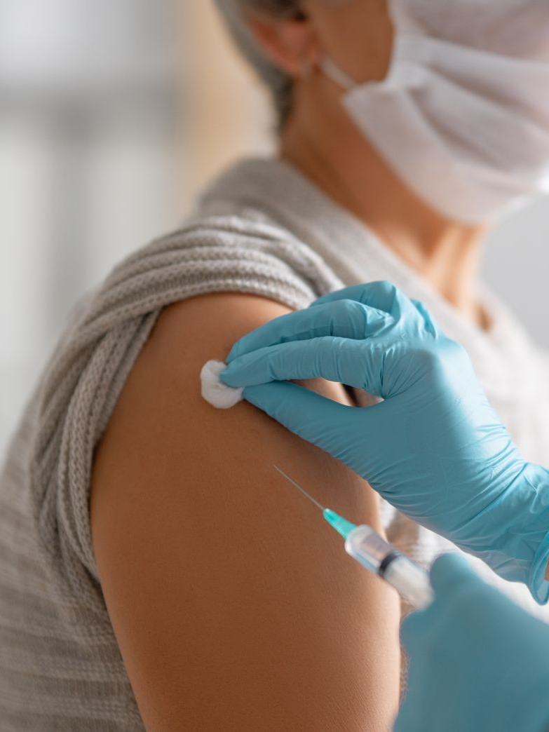 Une femme portant un masque en train de recevoir un vaccin