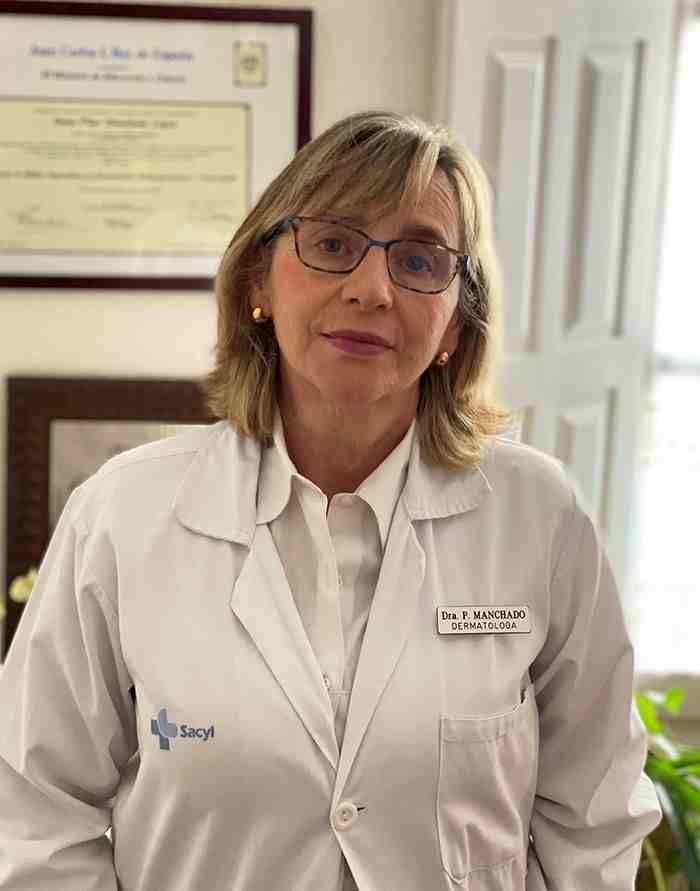 Una mujer con una bata blanca y gafas está parada en una habitación.