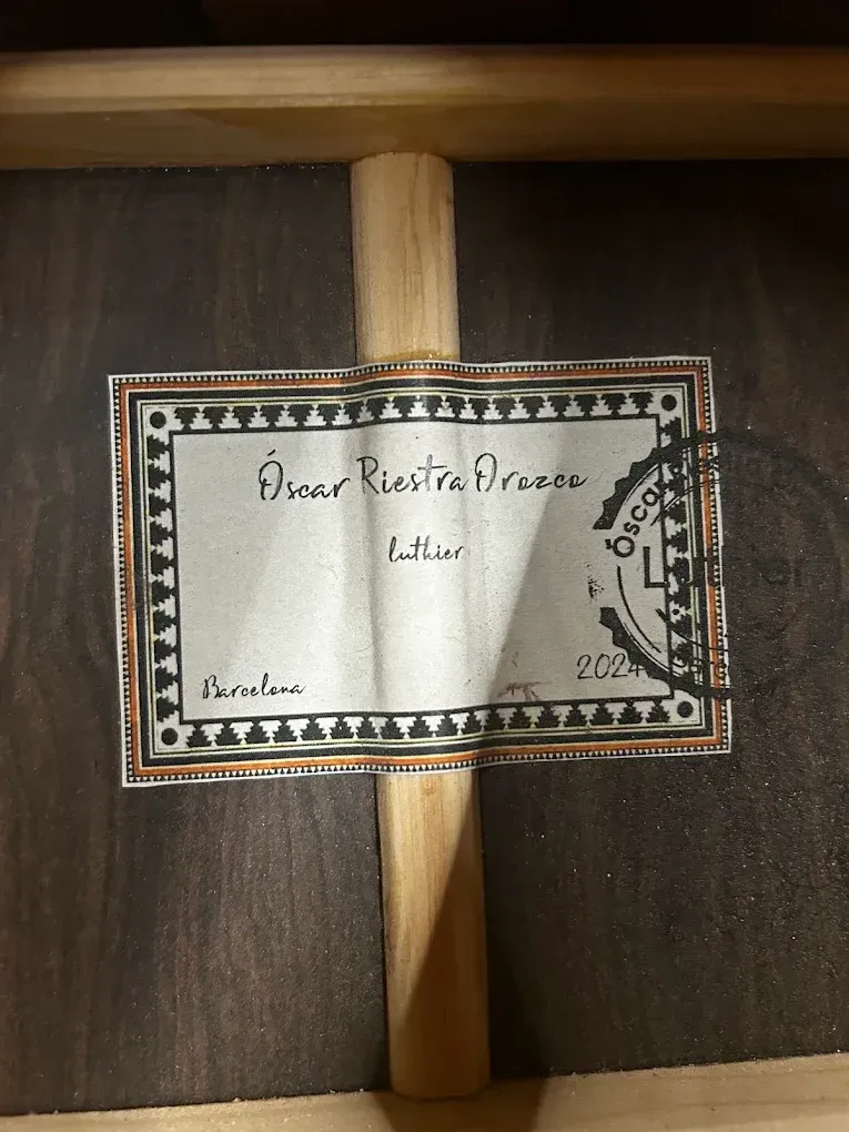 Una etiqueta rectangular en el interior de una guitarra, firmada