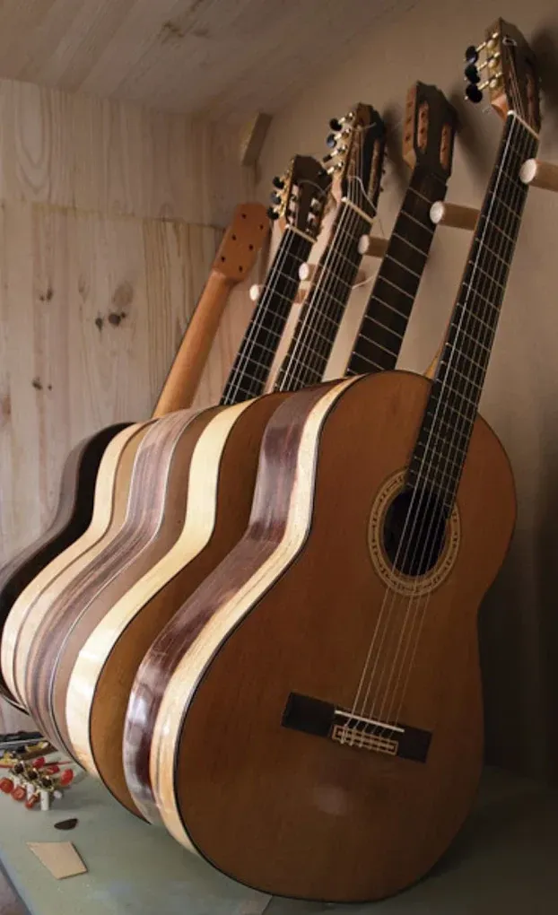 Varias guitarras acústicas estaban alineadas en ángulo contra una pared revestida de paneles de madera clara.