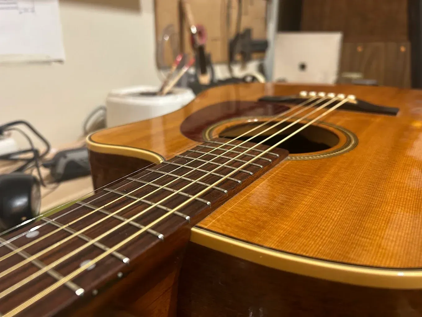 Primer plano y vista desde un ángulo bajo del mástil, las cuerdas y el cuerpo de una guitarra acústica