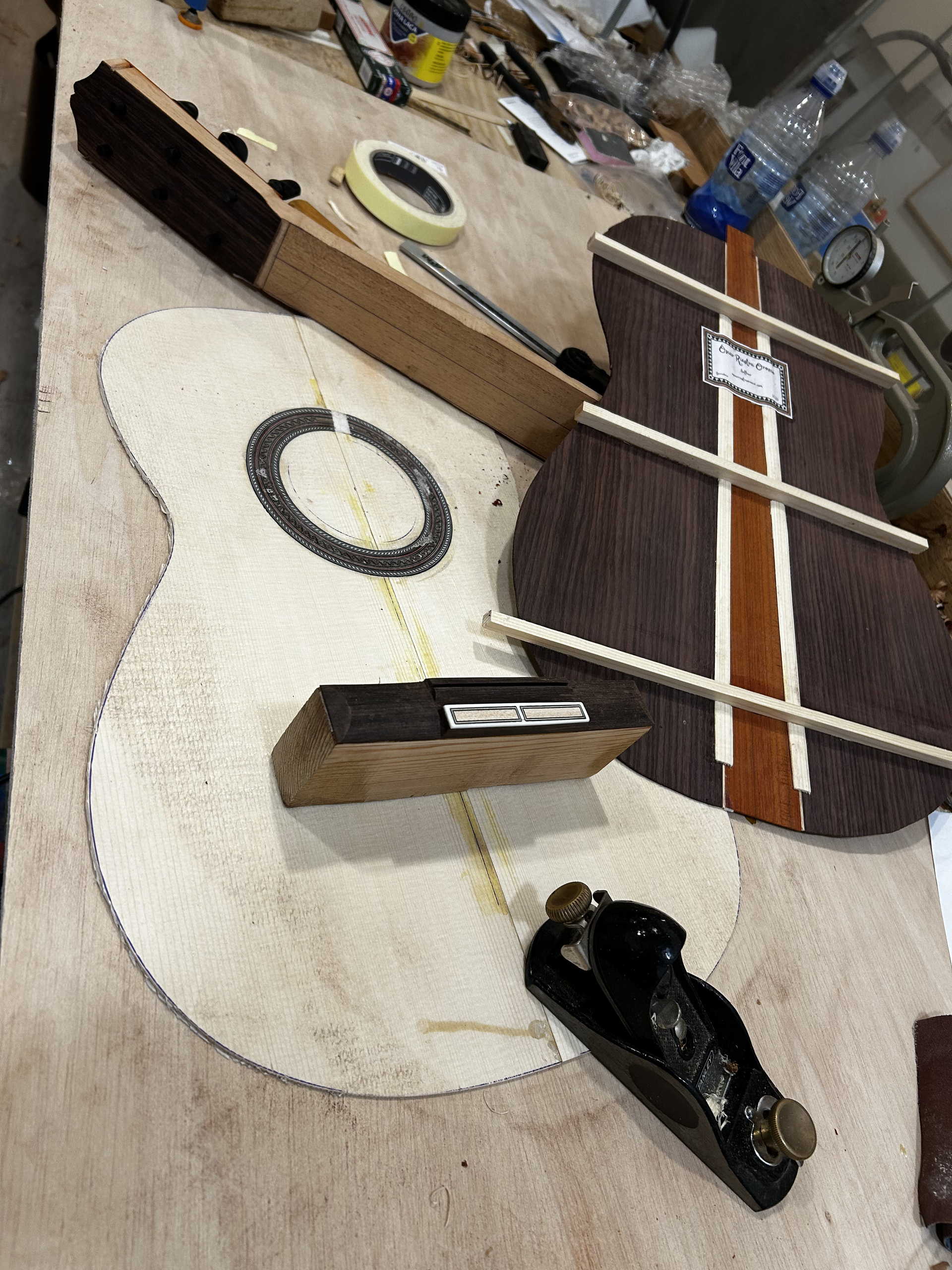 Una mano descansa sobre el diapasón de una guitarra de madera oscura, marcado con líneas de trastes