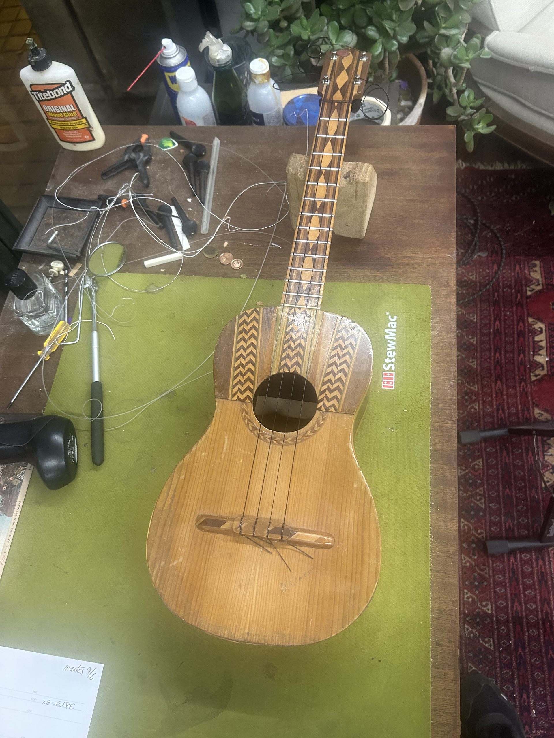 Primer plano de unas manos que pasan una cuerda de nailon a través del puente de una guitarra acústica de madera.
