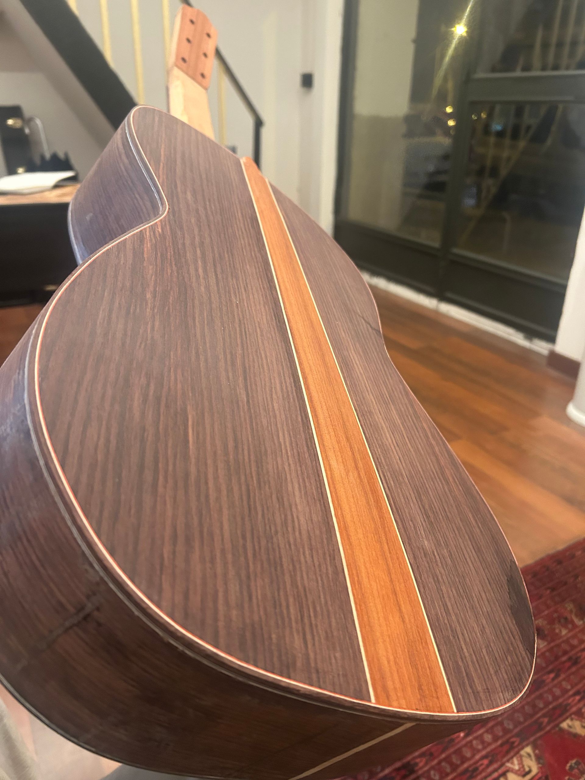 Vista de cerca de la parte posterior de una guitarra acústica de madera que presenta una veta oscura